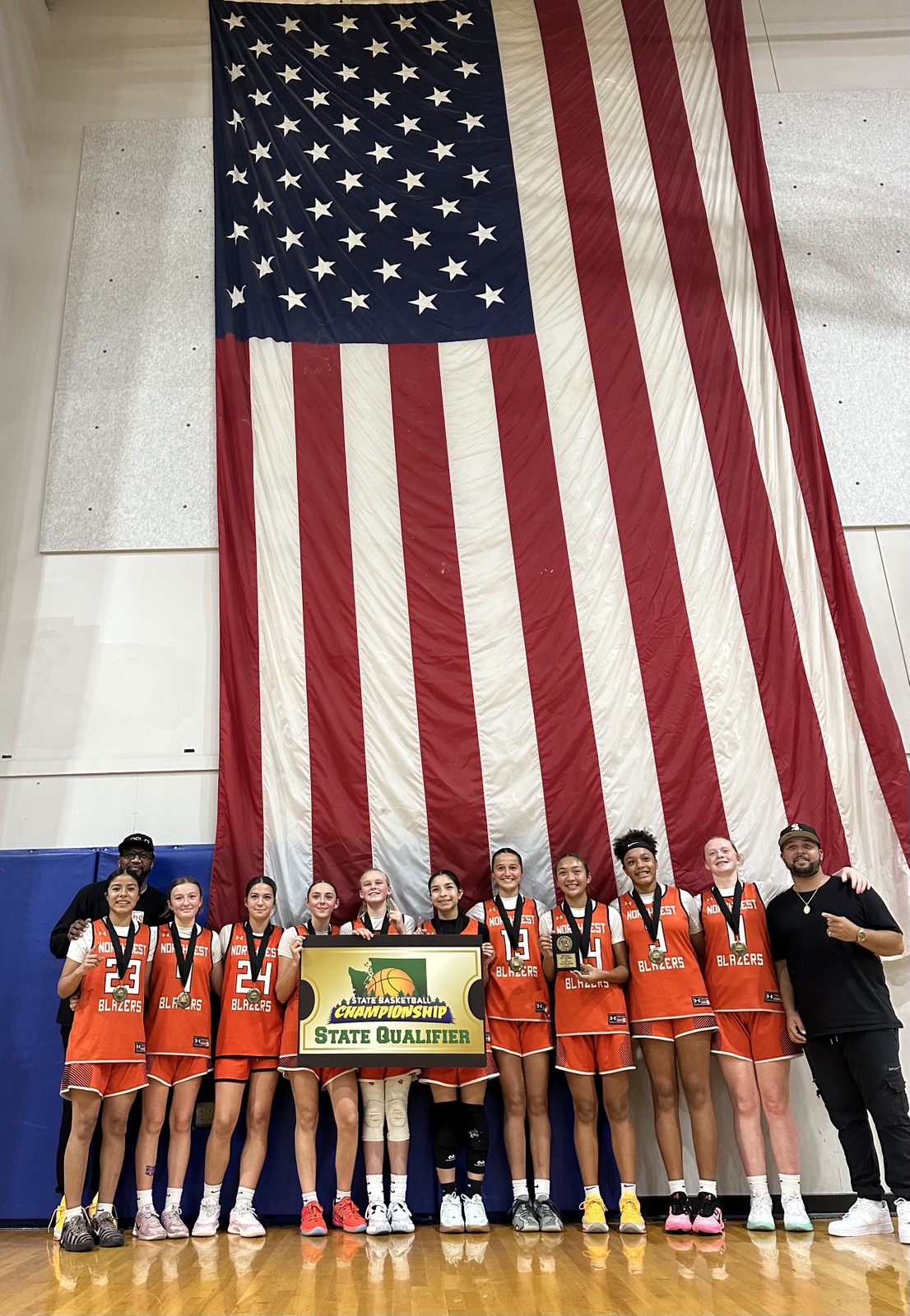 Northwest Blazers state qualifier team photo under a large American flag.