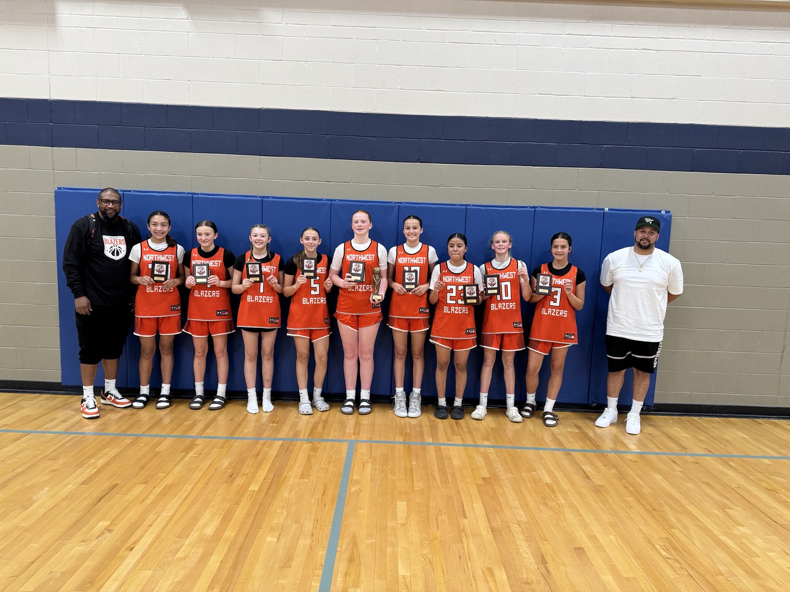 Northwest Blazers players and coaches holding individual awards in a gym.